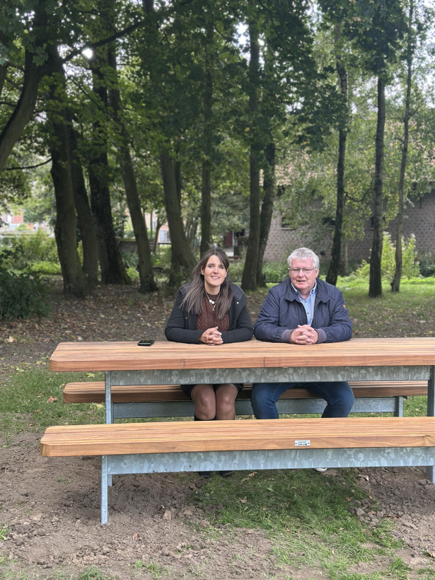 Jan en Saraï zitten aan een nieuwe picknickbank in het Sportpark